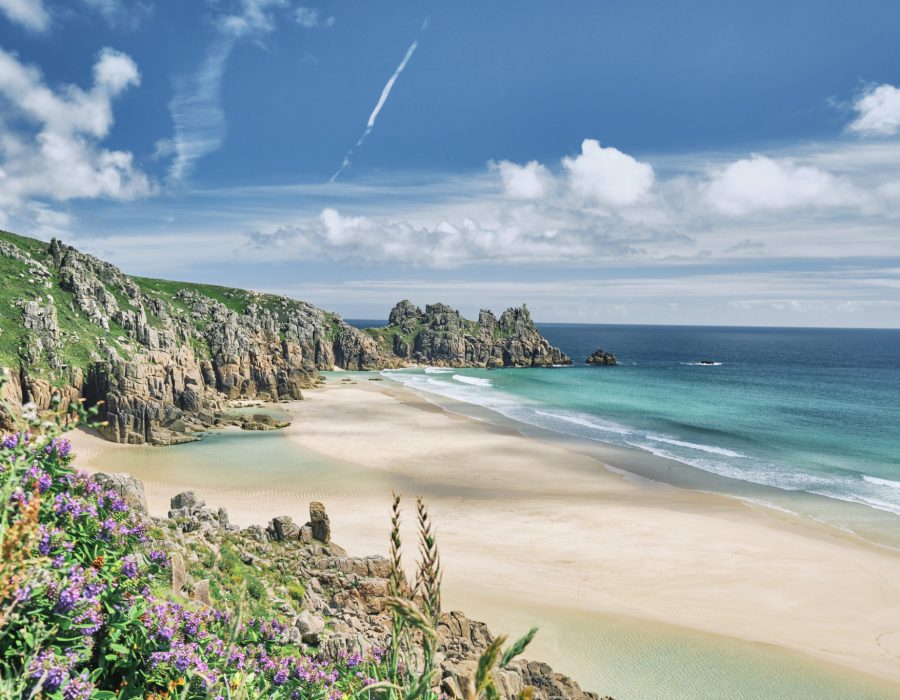 Scenic views across Pedn Vounder Beach towards Logan's Rock, Cornwall on a sunny June day.